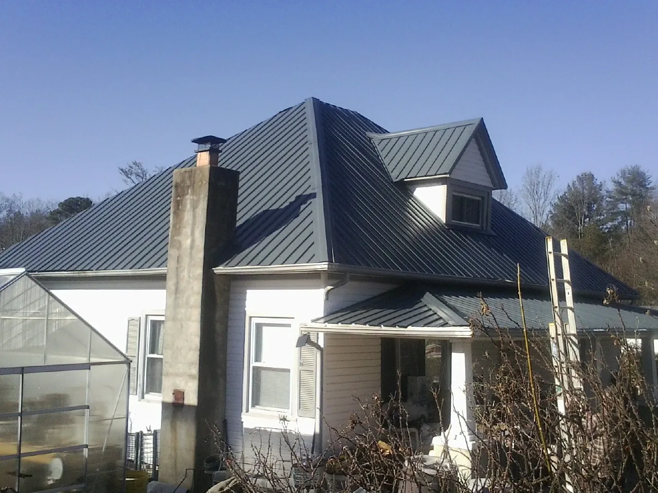 Dark blue standing seam metal roof on a white farmhouse with dormer — Slate & Tile Roof Repair by Roofing Brothers in Kahlotus