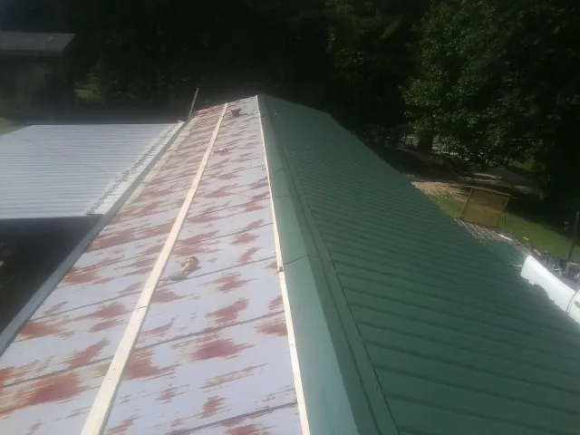 Old rusted panels beside newly installed green metal roofing — Wind Damage Roof Repair by Roofing Brothers in Kahlotus