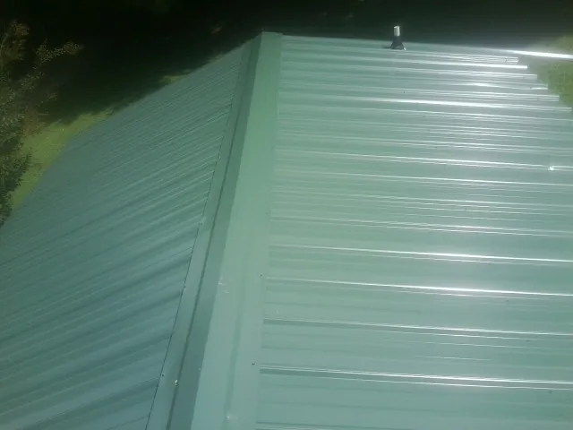 New green metal panels meeting at the ridge of a roof — Flat Roof Repair work by our crew in Kahlotus