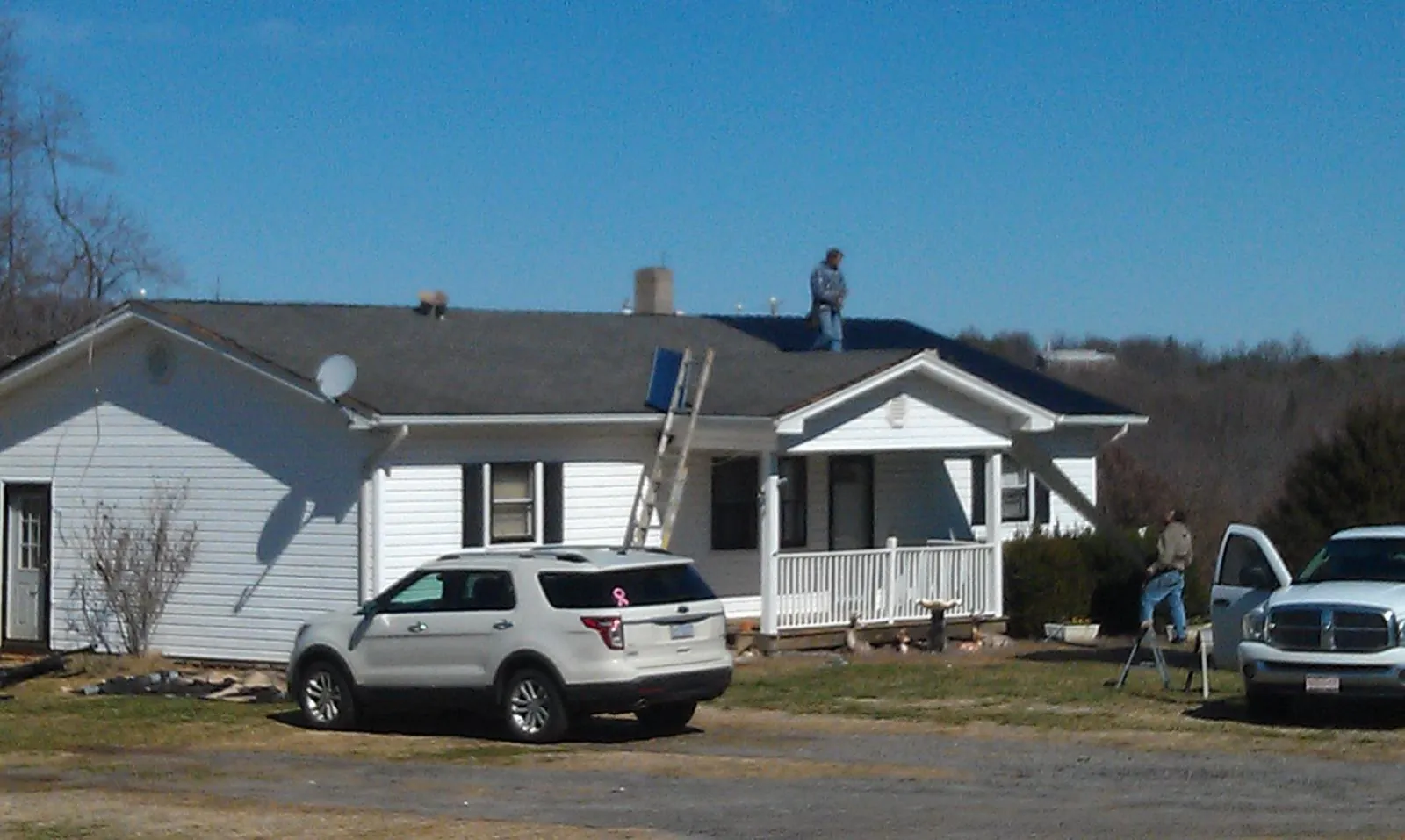 Roofers stripping shingles from a white ranch house roof in Kahlotus
