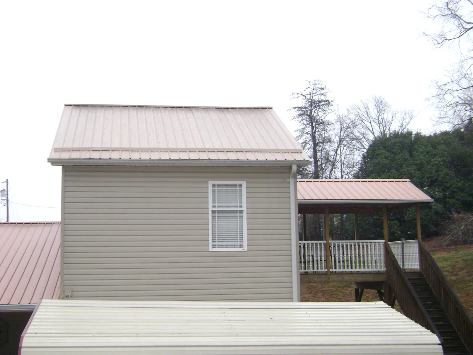 Tan metal roofs on a two story addition and attached porch, from a Roof Replacement job in Kahlotus