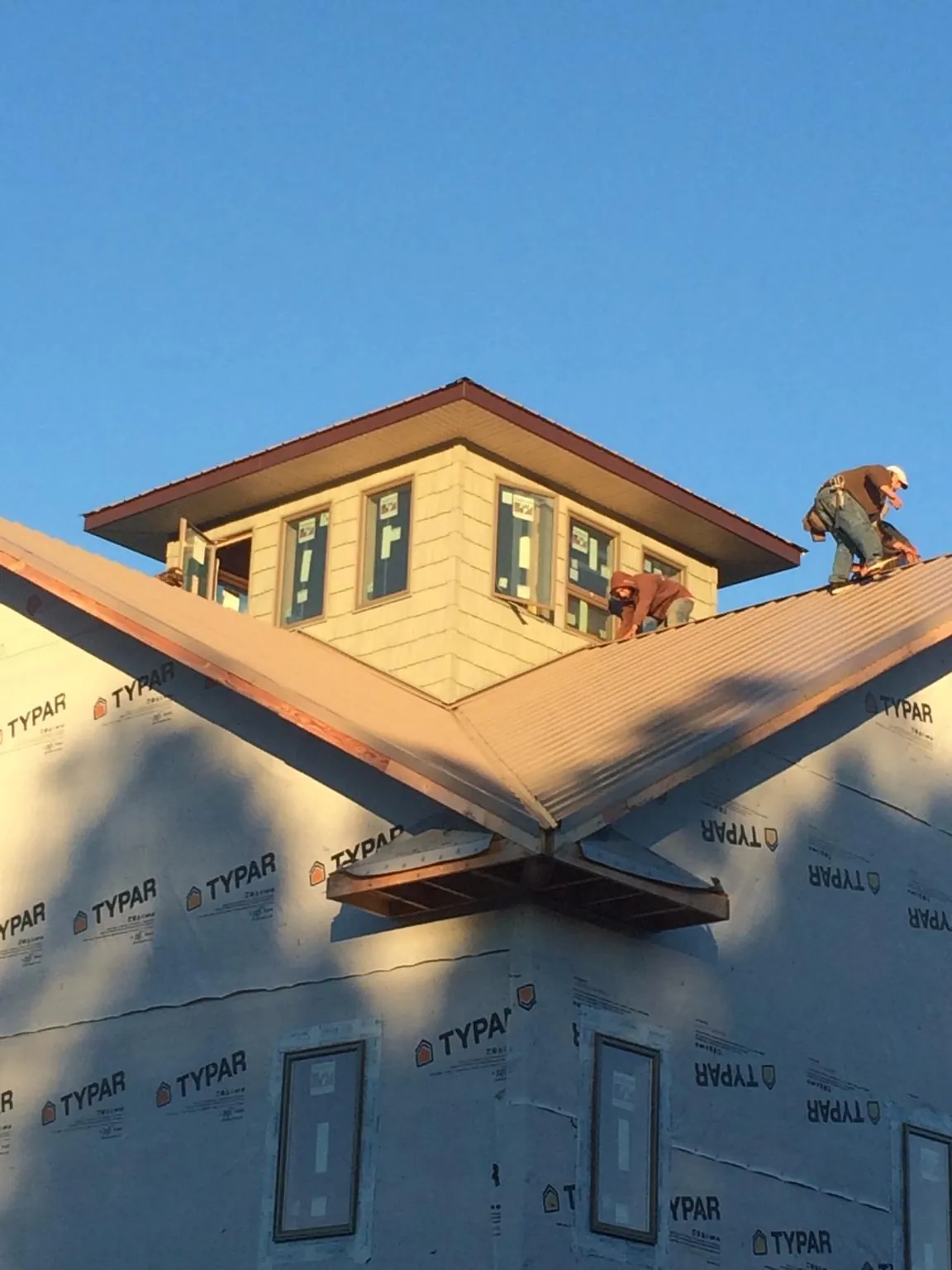 Roofers working around a rooftop cupola on a new metal roof at sunset — Roof Waterproofing in Kahlotus by Roofing Brothers